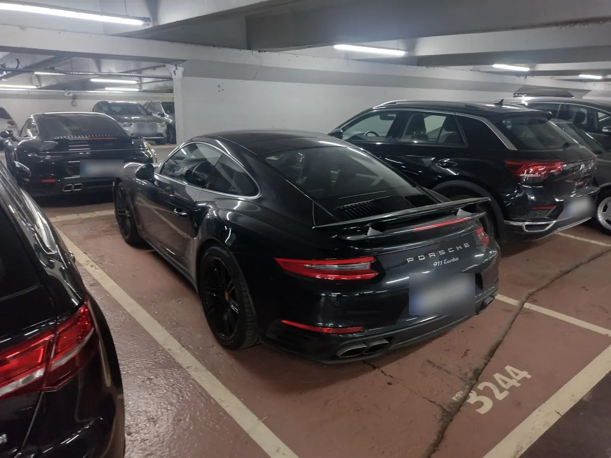Rear three-quarter view of a black Porsche 911 Turbo (991.2) in a parking garage