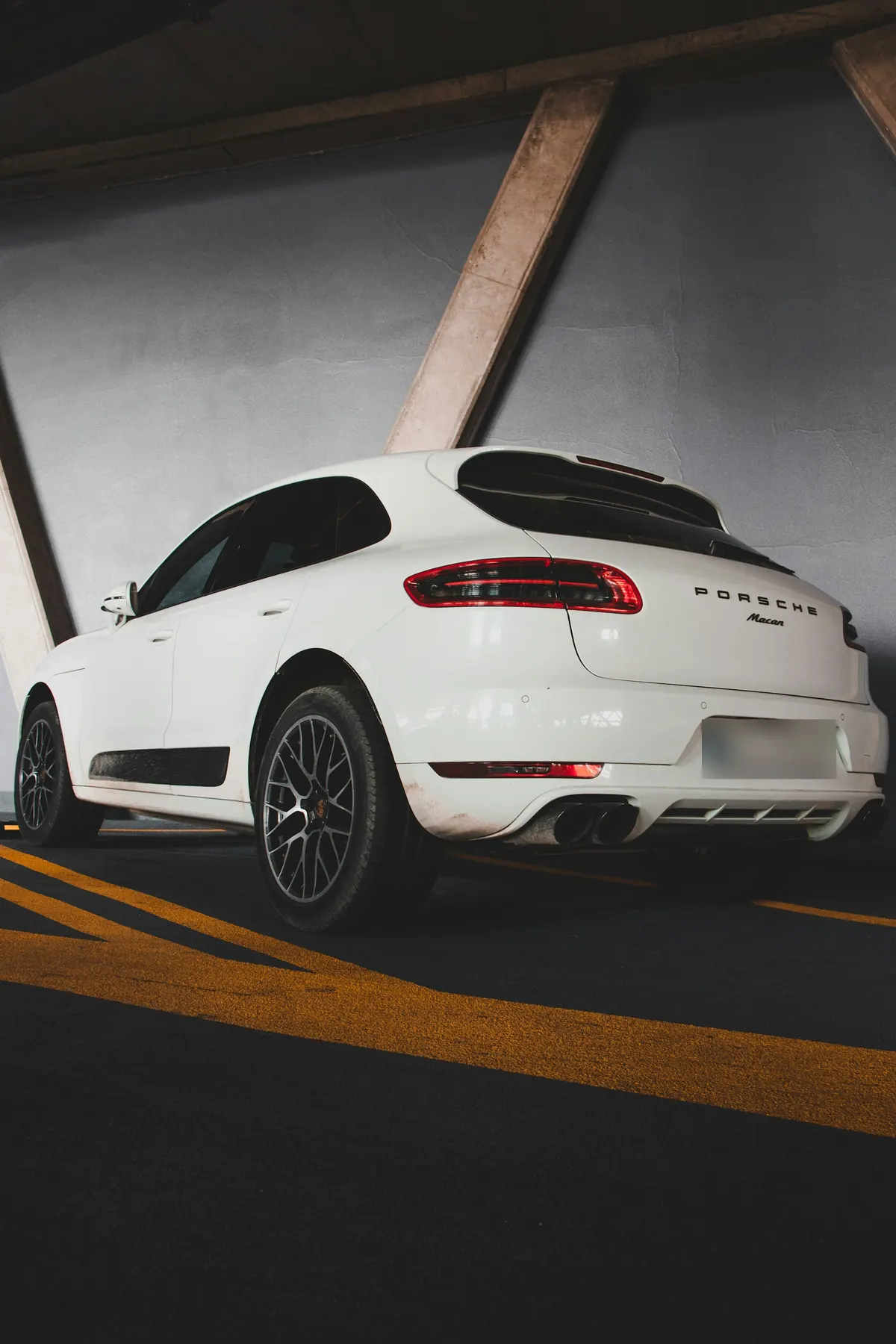 Rear three-quarter view of a white Porsche Macan (95B.1) in a parking garage