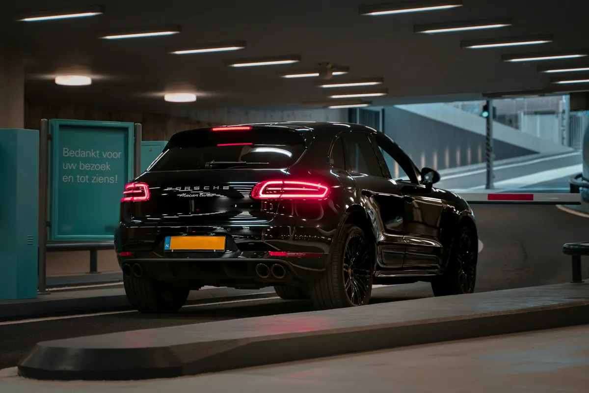 Rear three-quarter view of a black Porsche Macan Turbo (95B.1) in a parking garage