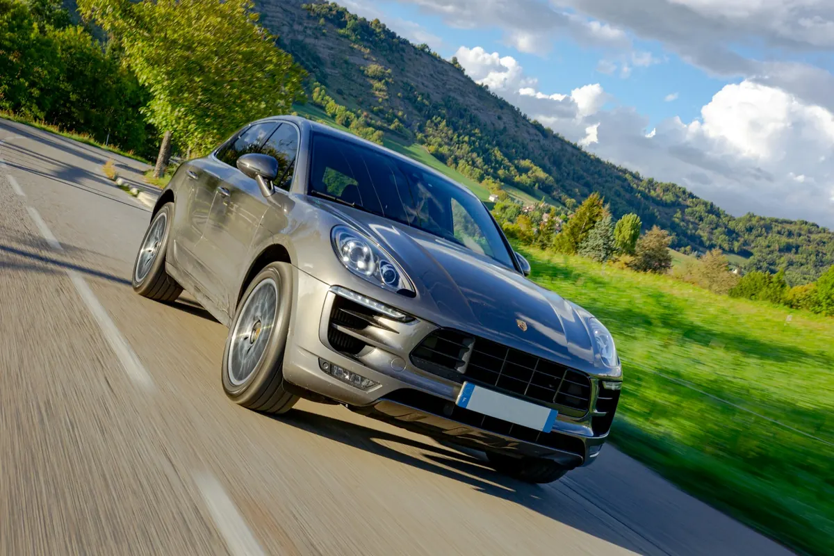 Front three-quarter view of a grey Porsche Macan Turbo with Performance Package (95B.1) driving on a country road