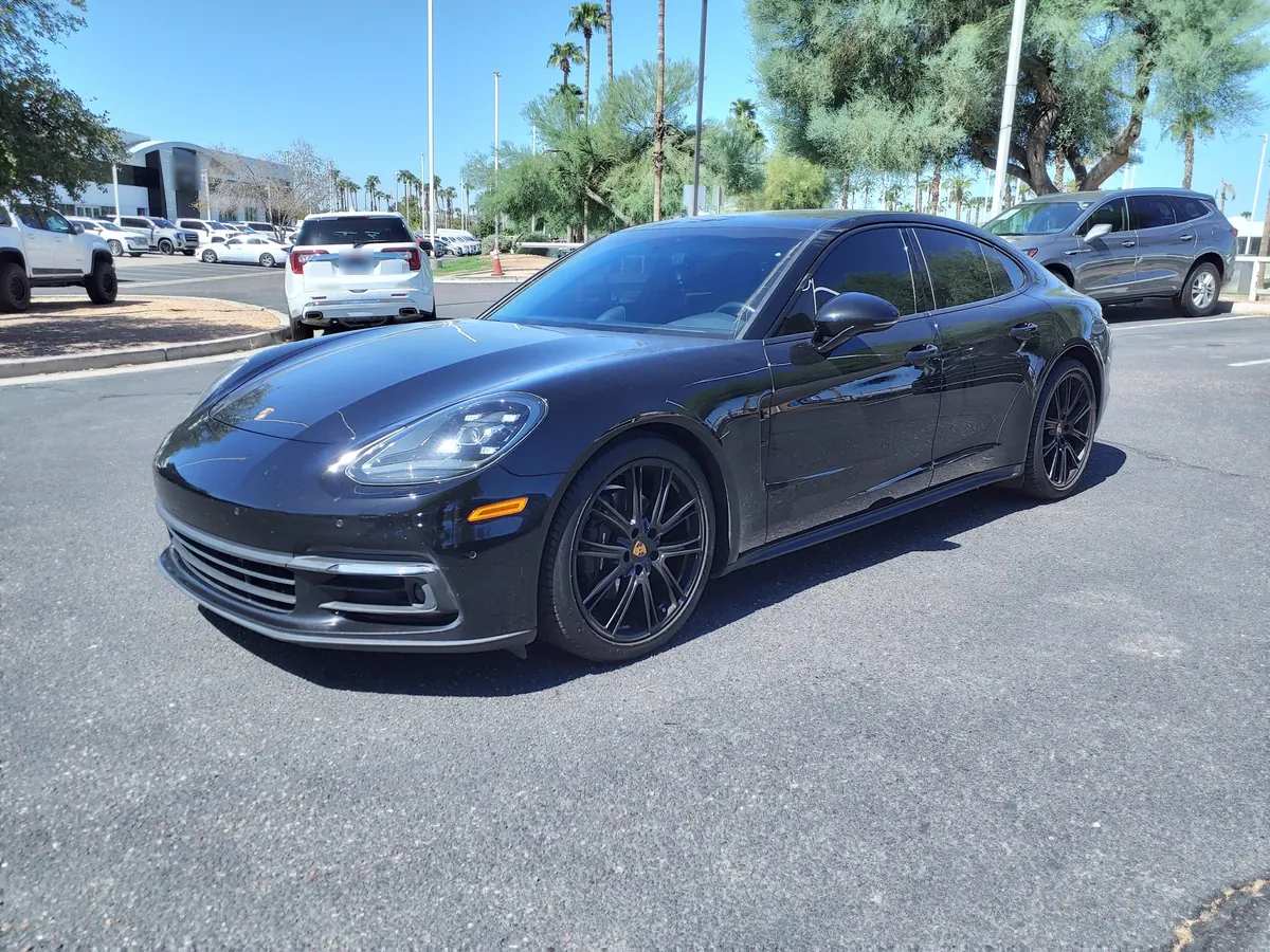 Front three-quarter view of a black Porsche Panamera (971.2) in a dealership parking lot