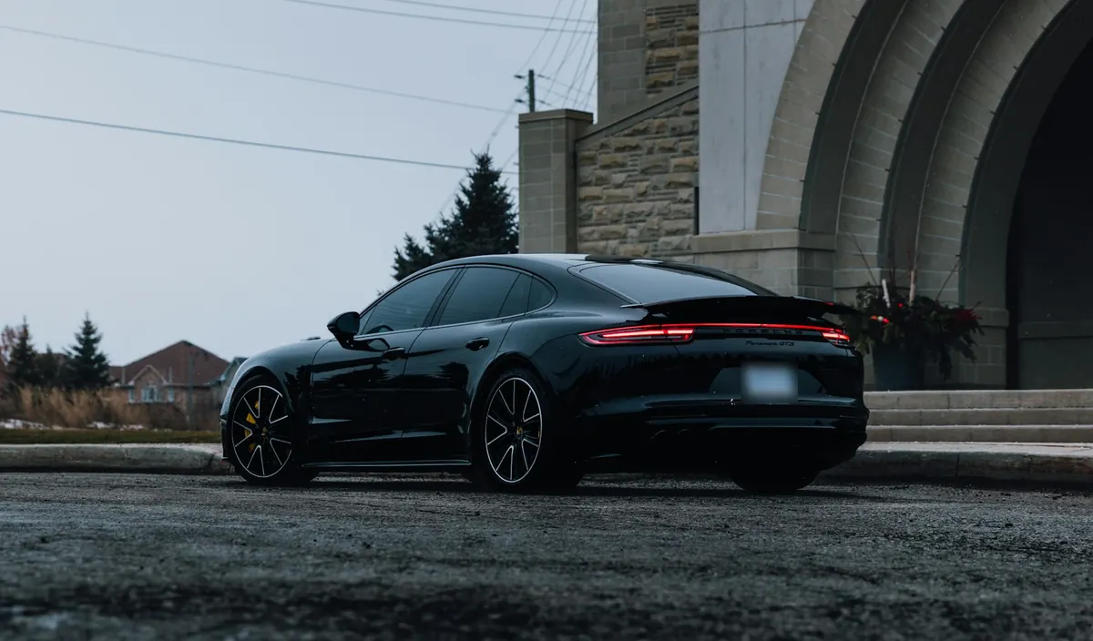 Rear three-quarter view of a black Porsche Panamera GTS (971.1) in front of a stone archway