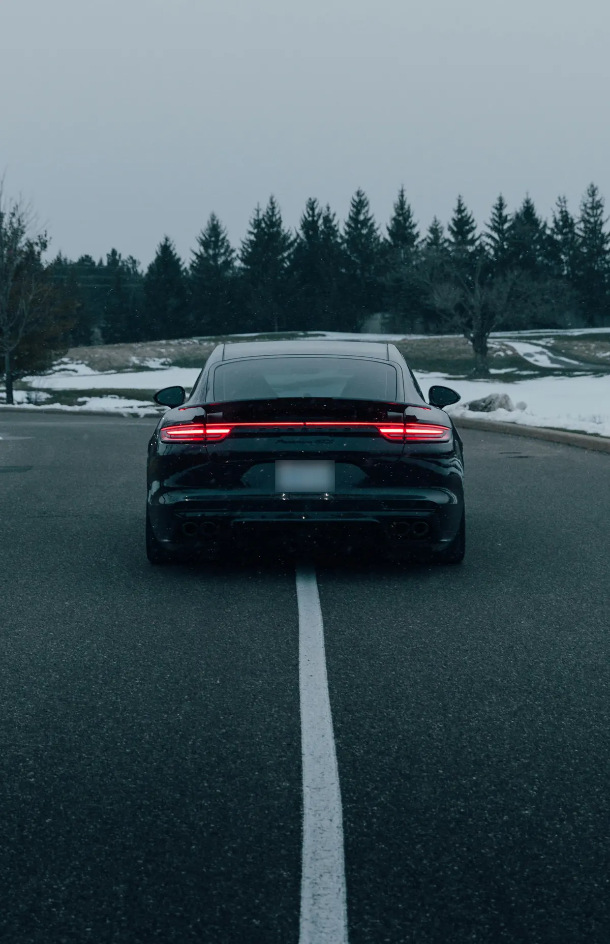 Rear view of a black Porsche Panamera GTS (971.2) on a road in winter