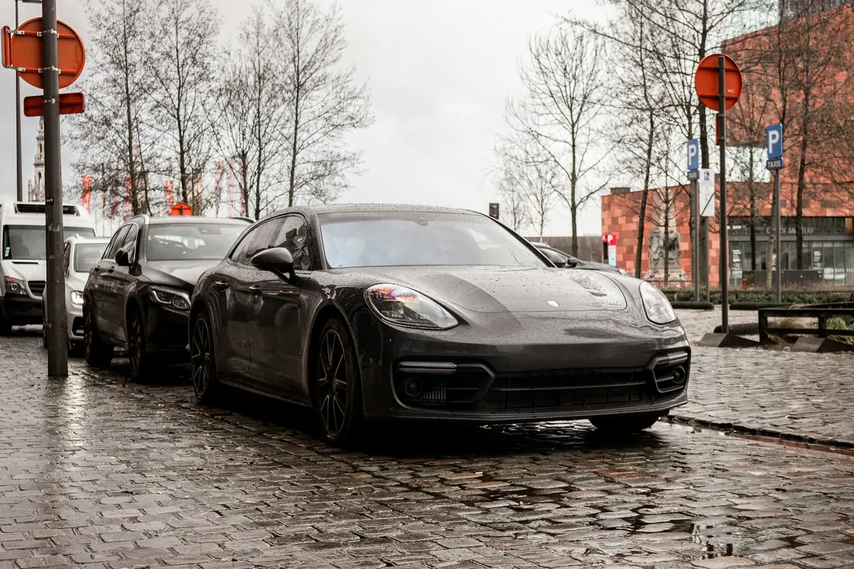 Front three-quarter view of a dark grey Porsche Panamera Turbo S (971.2) on a wet cobblestone street
