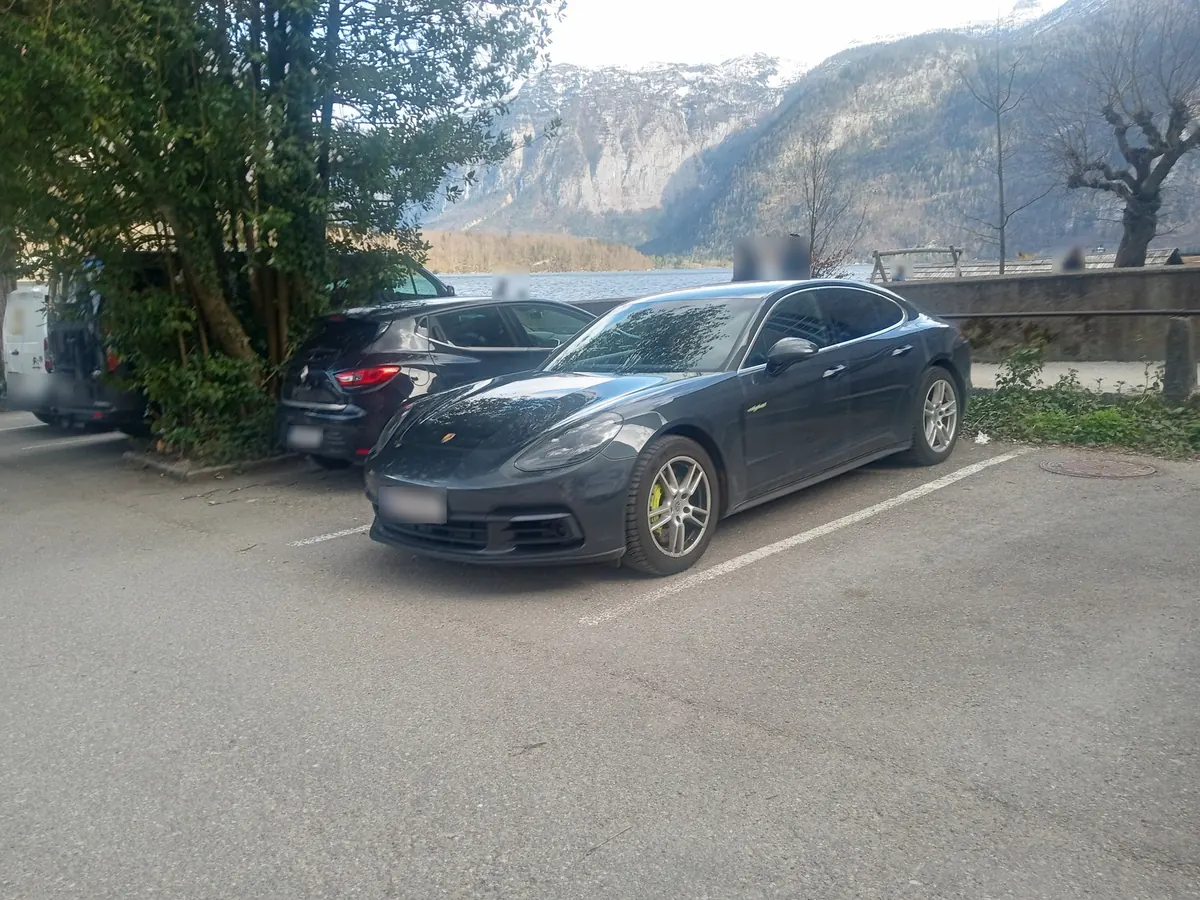 Front three-quarter view of a dark grey Porsche Panamera Turbo S E-Hybrid (971.1) parked by a mountain lake