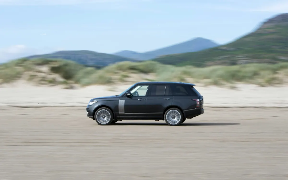 Side view of a dark grey Range Rover Supercharged V8 (L405) driving across a beach