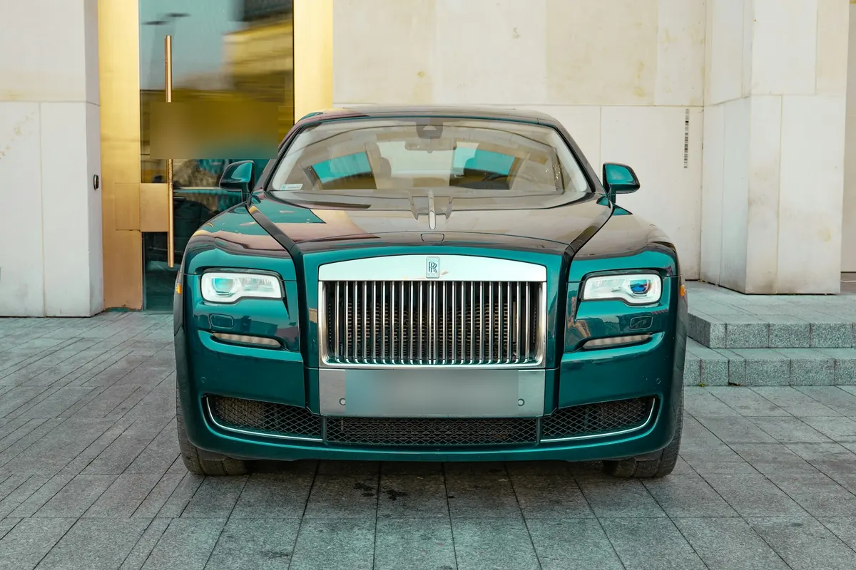Front view of a dark green Rolls-Royce Ghost Series II (2014–2020) parked outside a building