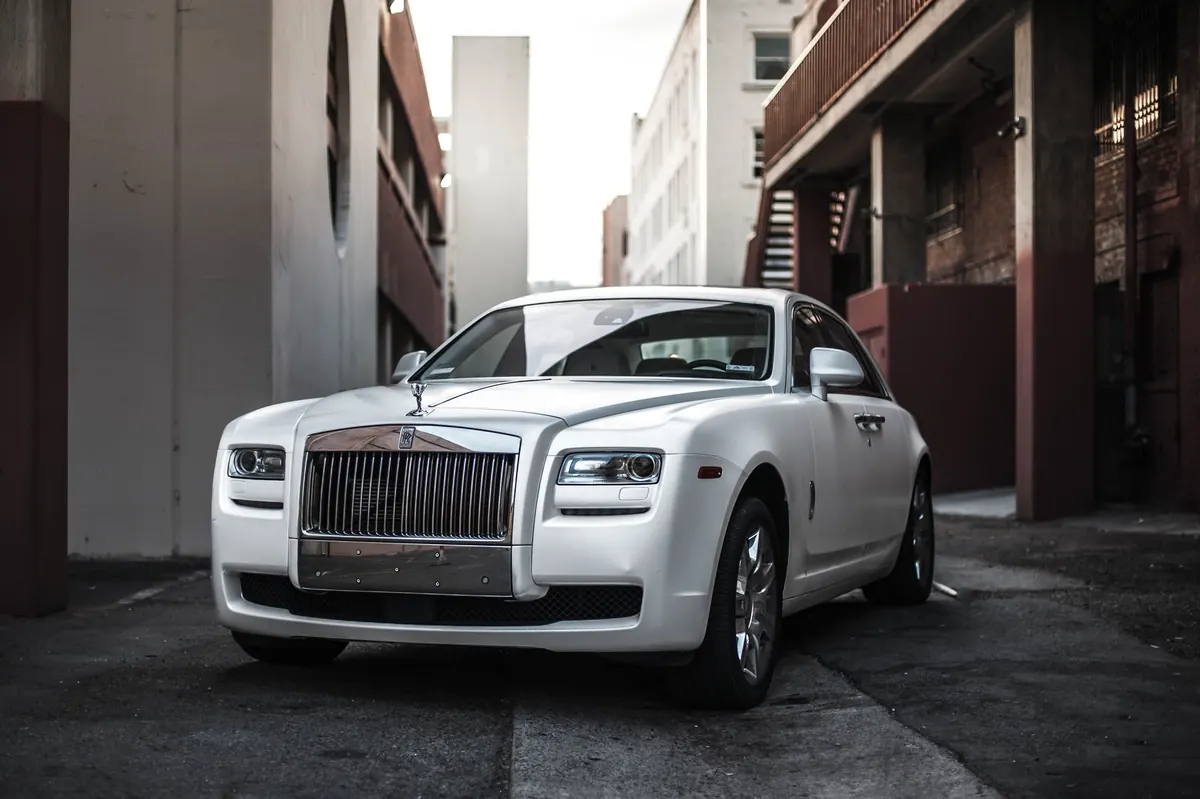 Front three-quarter view of a white Rolls-Royce Ghost Series II Black Badge (2016–2020) parked in an alley