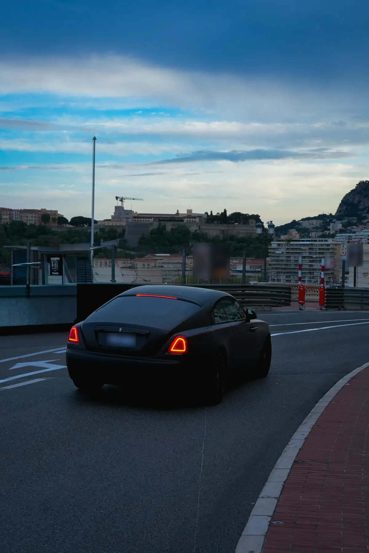 Rear three-quarter view of a matte black Rolls-Royce Wraith Black Badge on a street in Monaco