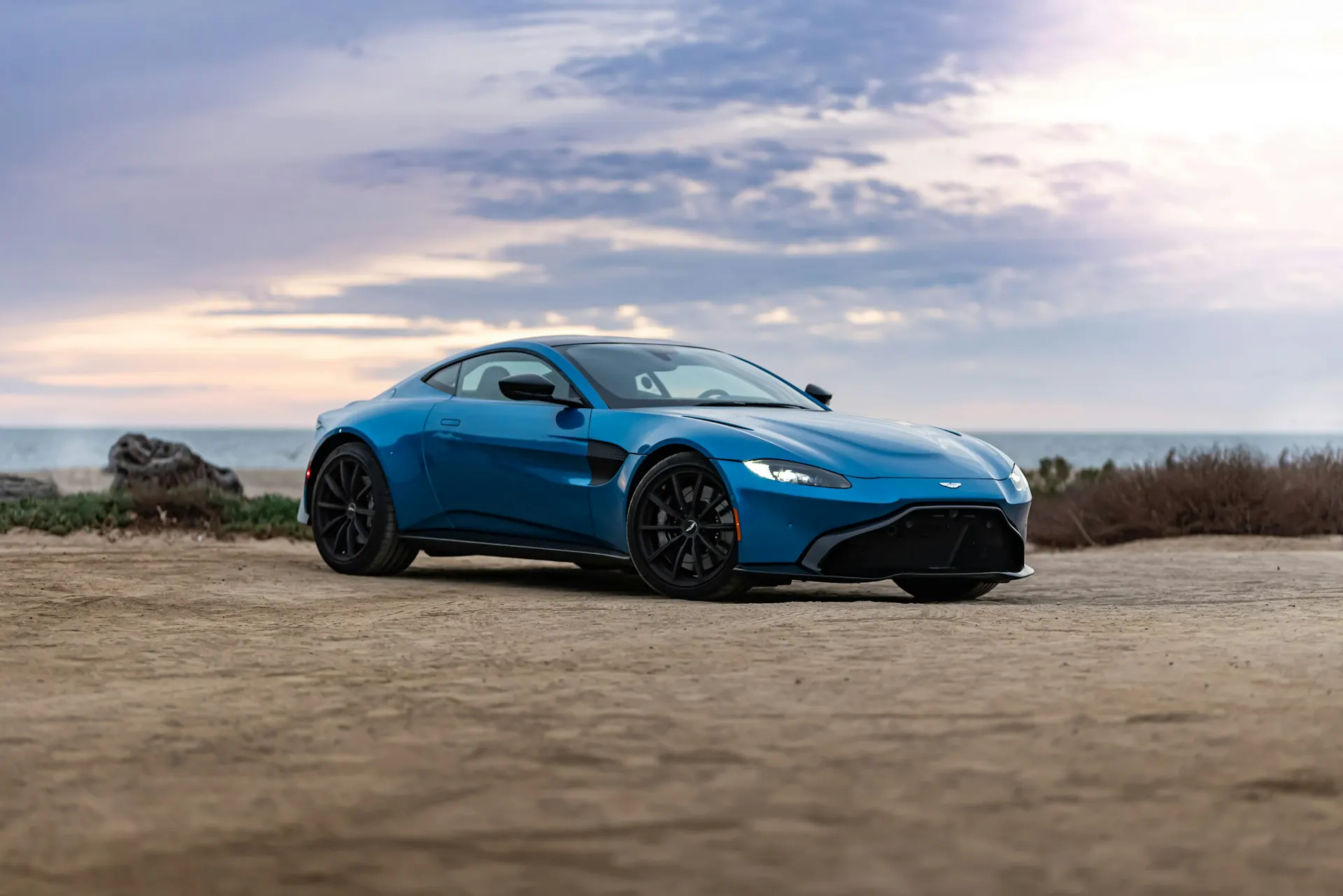 Blue Aston Martin Vantage parked by the sea
