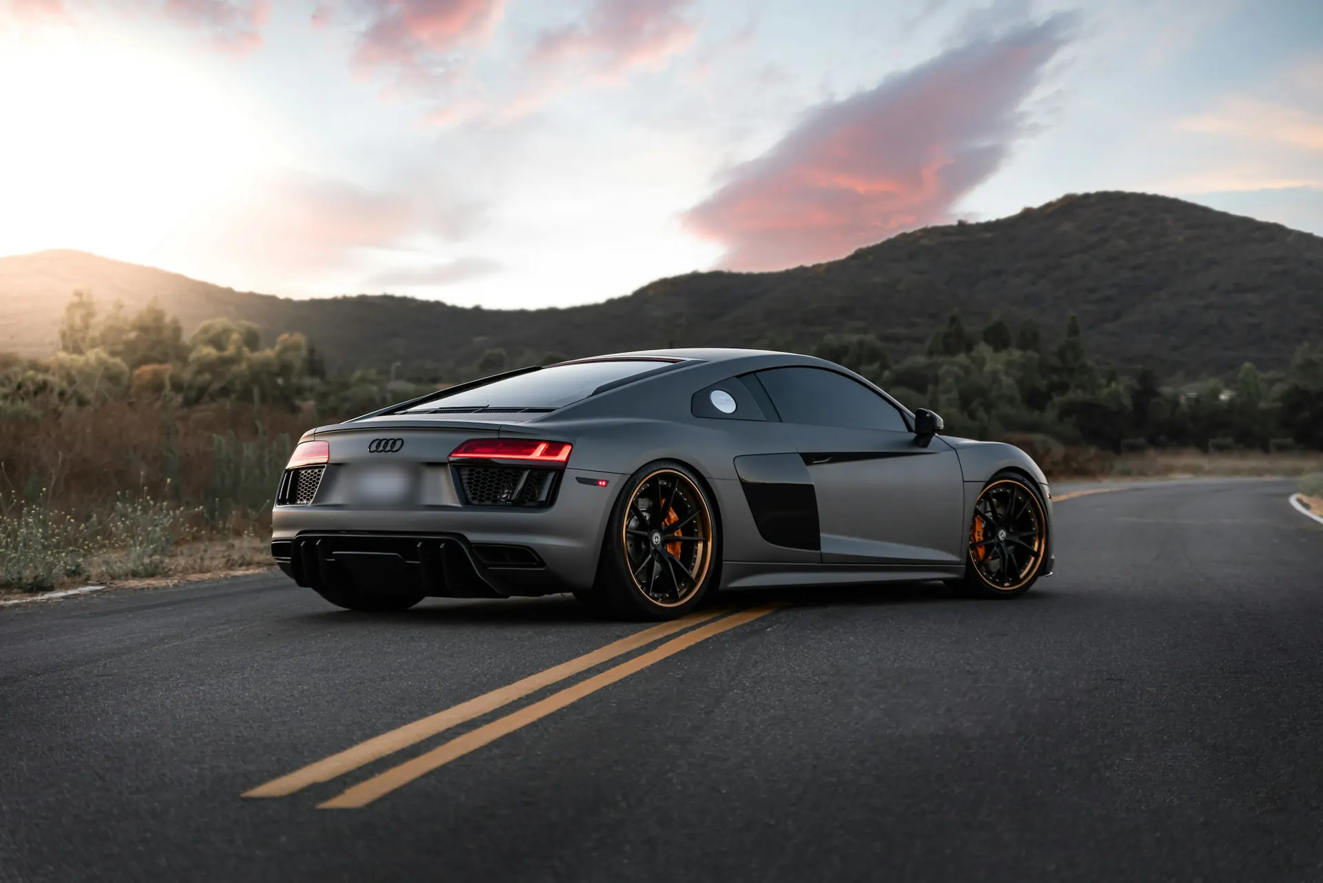 Grey Audi R8 on a mountain road at sunset