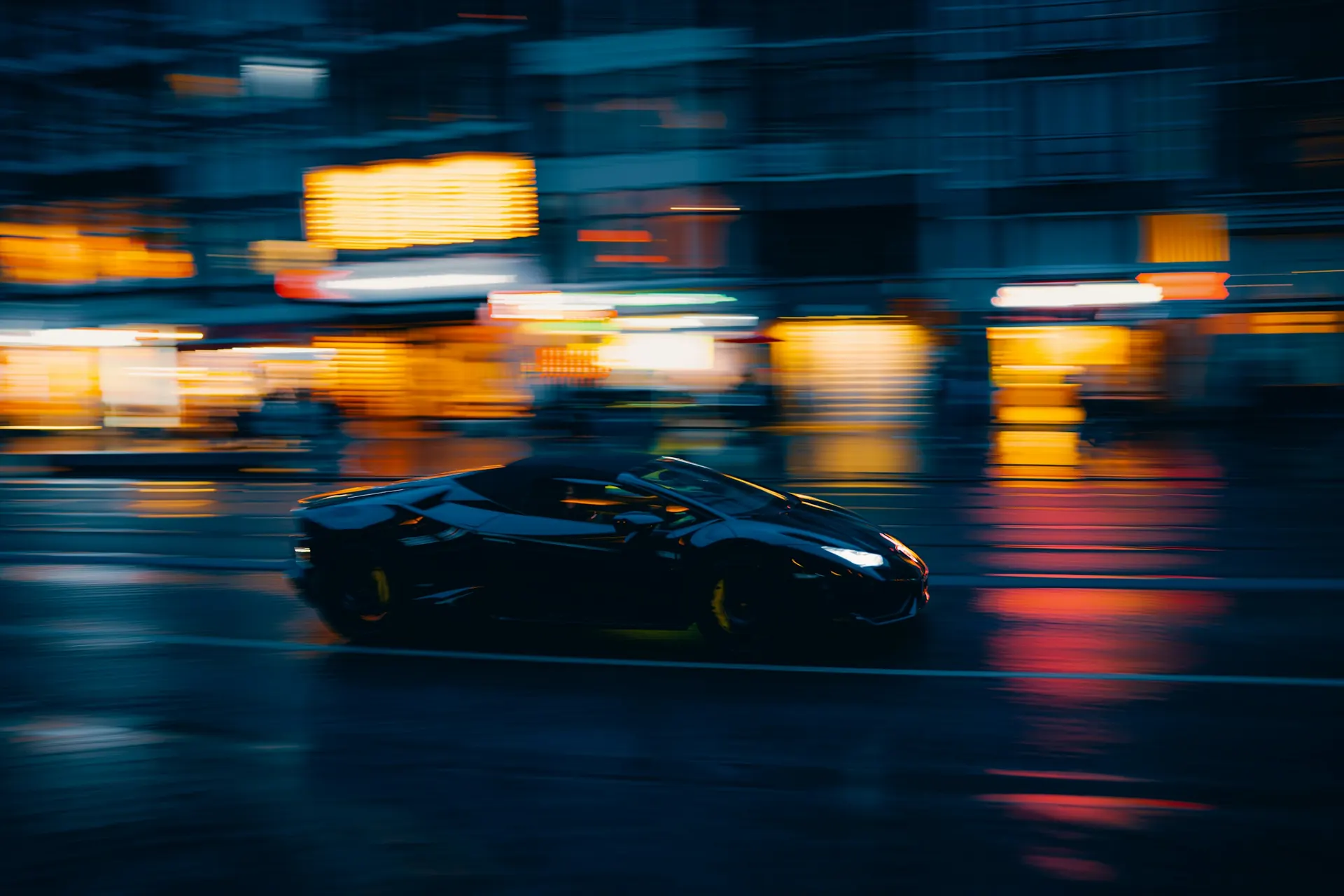 Dark supercar driving through a city street at night