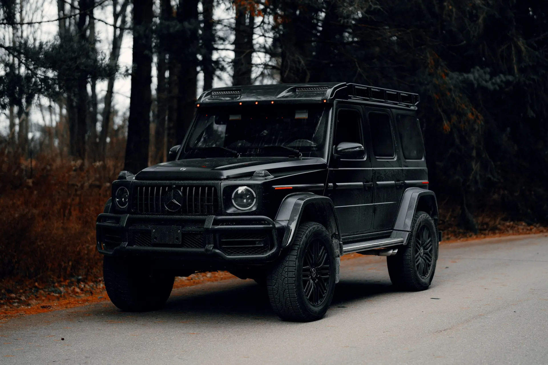 Black Mercedes-Benz G-Class with a roof rack on a forest road